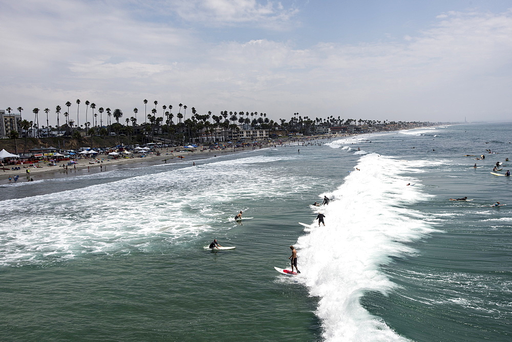 Surfers catch a "party wave" after taking part in a paddle out honoring local surfing legend known as Skydog at Oceanside Beach in Oceanside, Calif., on August 3, 2014.