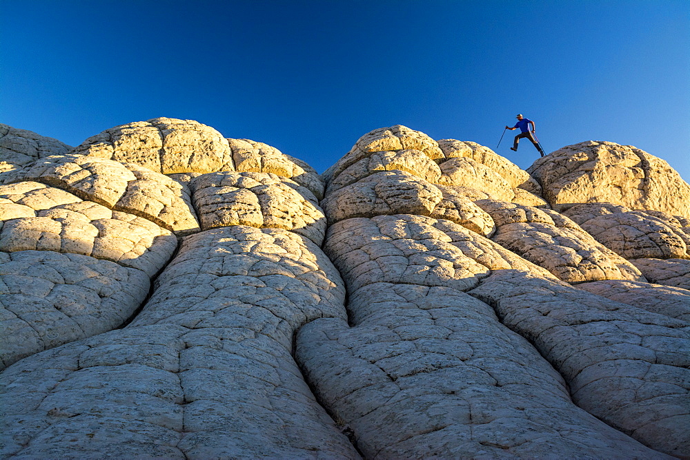 A man hiking along sandstone layers, White Pocket, Vermillion Cliffs National Monument, Kanab, Utah.