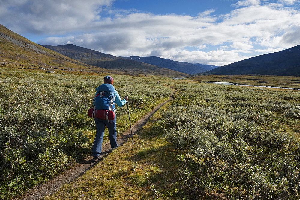 Hiker on trail through Tjäktjavagge south of Singi hut, Kungsleden trail, Lapland, Sweden