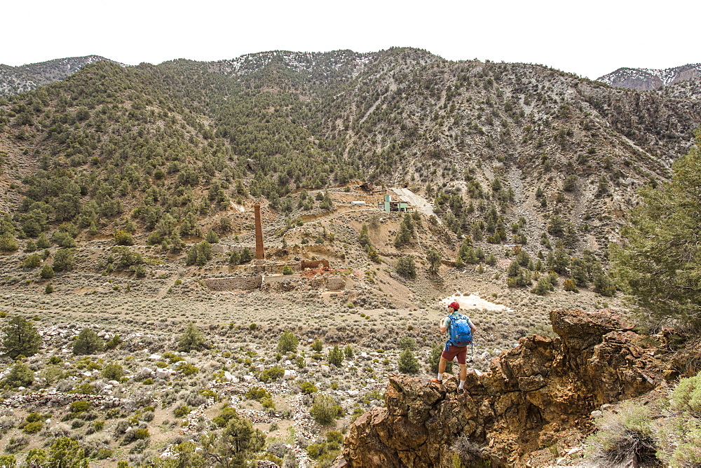 SURPRISE CANYON, DEATH VALLEY, CA, USA. A young man takes a break at an overlook of an abandoned silver mine in a dry, remote valley.