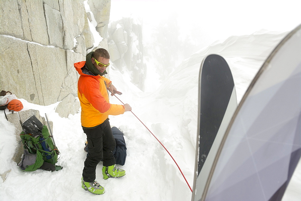 A man camped on the summit ridge after  climbing Thunderbolt Ridge in Hogum Fork while on a backcountry ski tour in Little Cottonwood Canyon, Lone Peak Wilderness, Uinta-Wasatch-Cache National Forest, Salt Lake City, Utah.