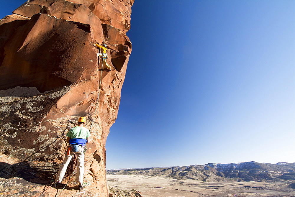 A man and woman rock  climbing a route called  Psycho Path on Psycho Tower above the Big Gypsum Valley, Naturita, Colorado.