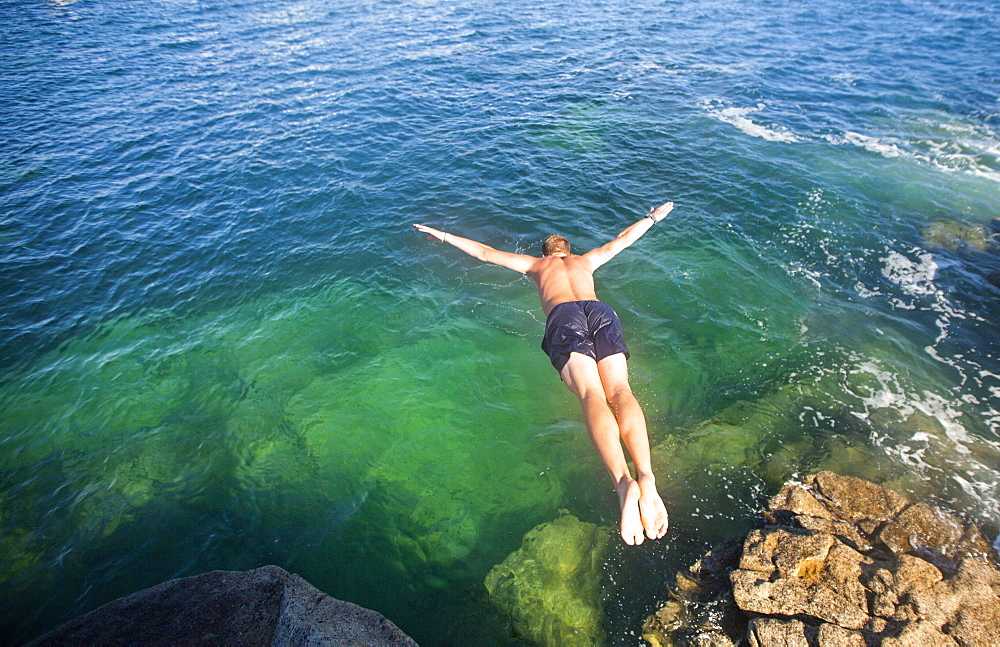 Shirtless Man Jumping In The Ocean Water