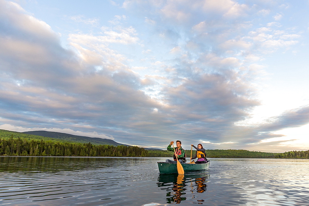 A Young Couple Paddles A Canoe On Long Pond In Maine's North Woods Near Greenville, Maine