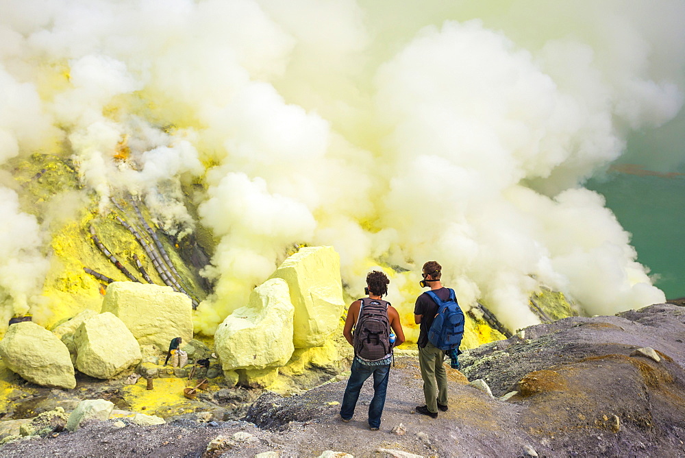 Two Men Exploring Sulfur Dioxide Smoke At Kawah Ijen, Java, Indonesia