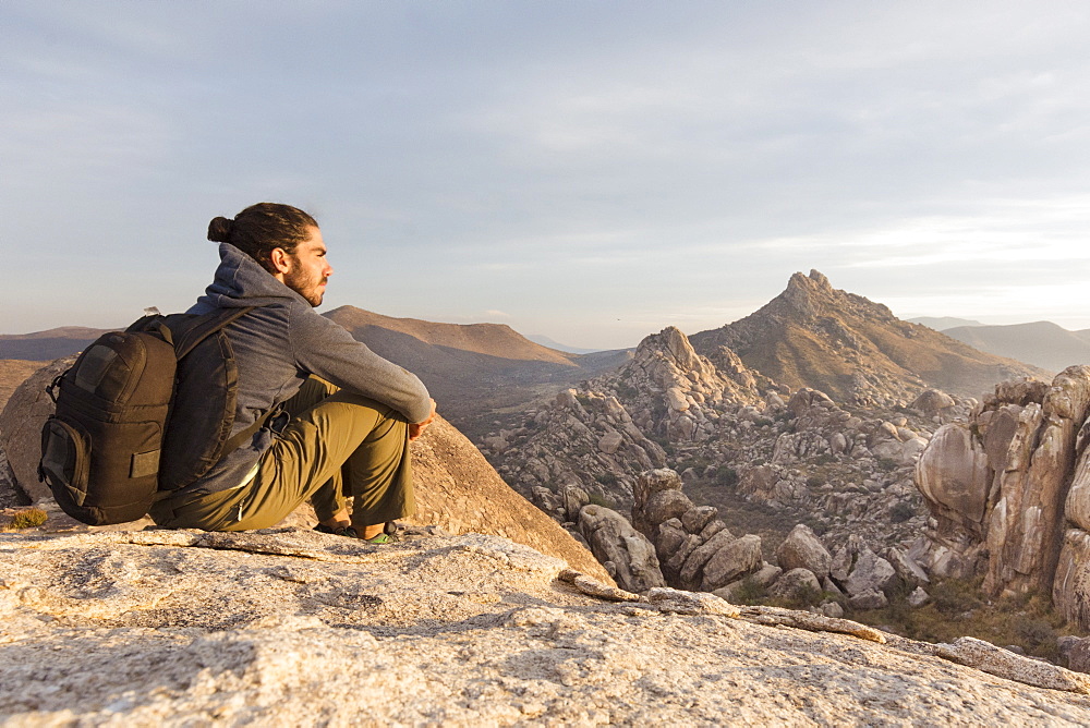 A Young Man Relaxing On Rock Exploring Desert Landscape