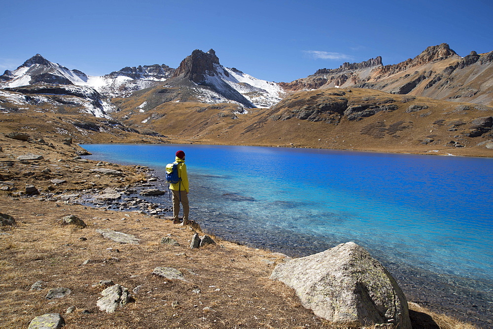 Young male stands at Ice Lake in the San Juan mountains of southern Colorado during a sunny fall afternoon