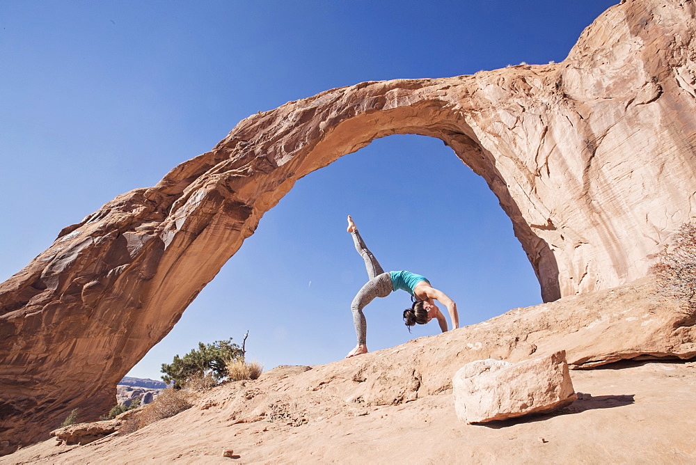 A Fit Young Woman Practices Yoga Under Corona Arch, Moab, Utah