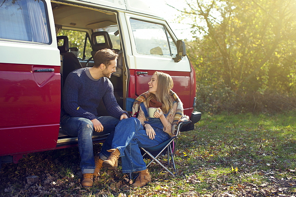 Young couple having coffee in front of caravan