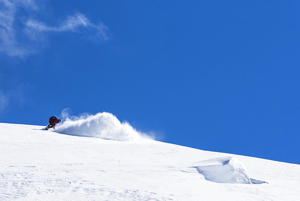 Professional Snowboarder Helen Schettini, rides fresh powder on a sunny day while snowboarding in Haines, Alaska.