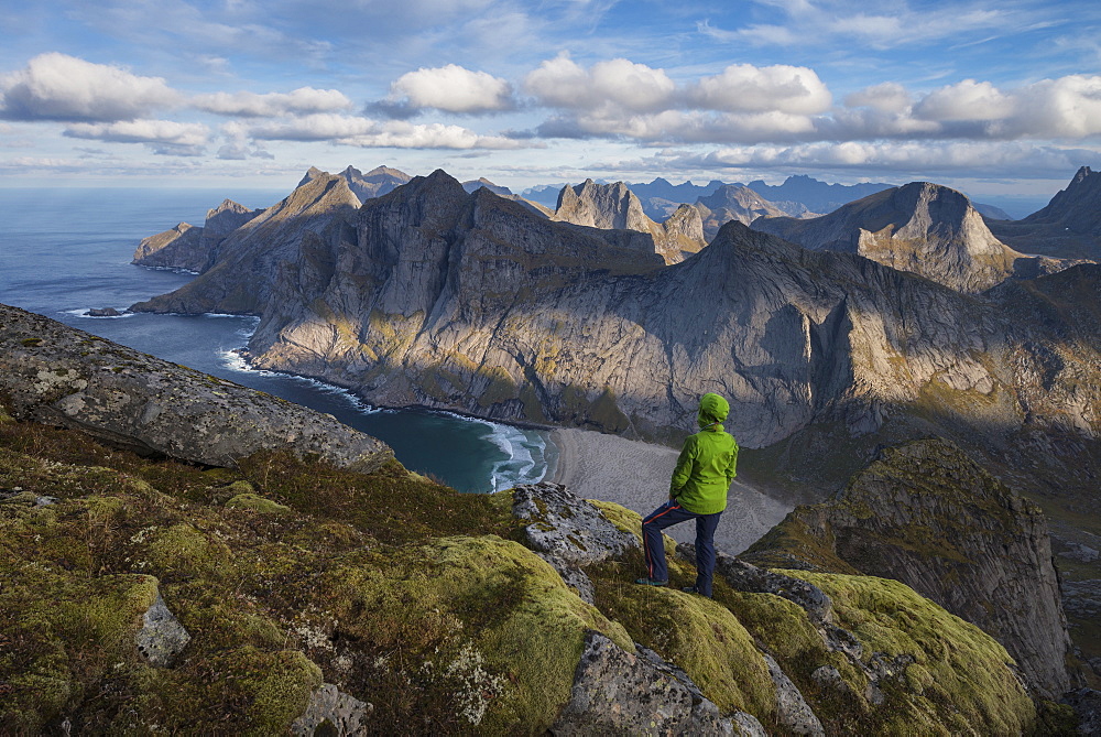 Female hiker takes in view over Bunes beach while hiking to Storskiva mountain peak, Moskenesøy, Lofoten Islands, Norway