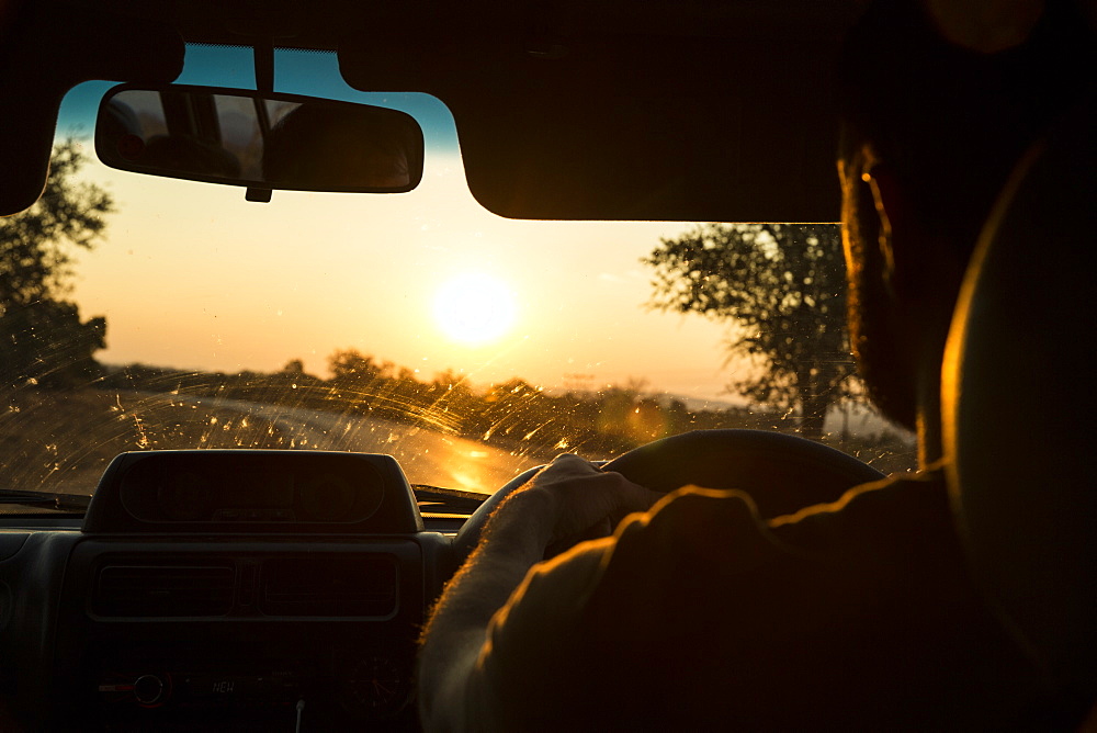 A male drives his truck towards the sunset in Zimbabwe