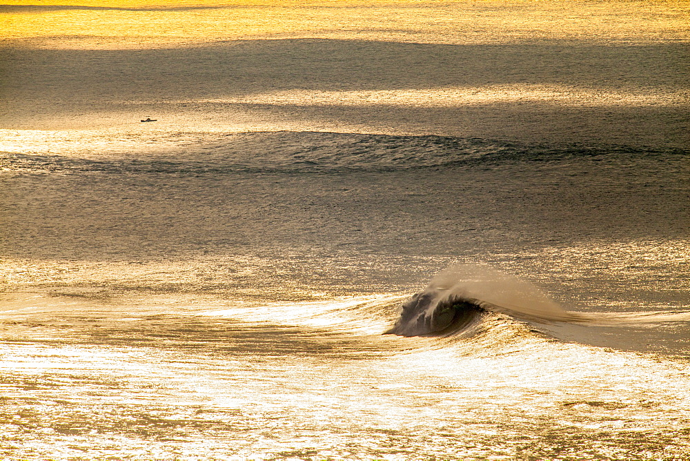 A huge wave off the lower north shore of Oahu, under golden Vog skies.