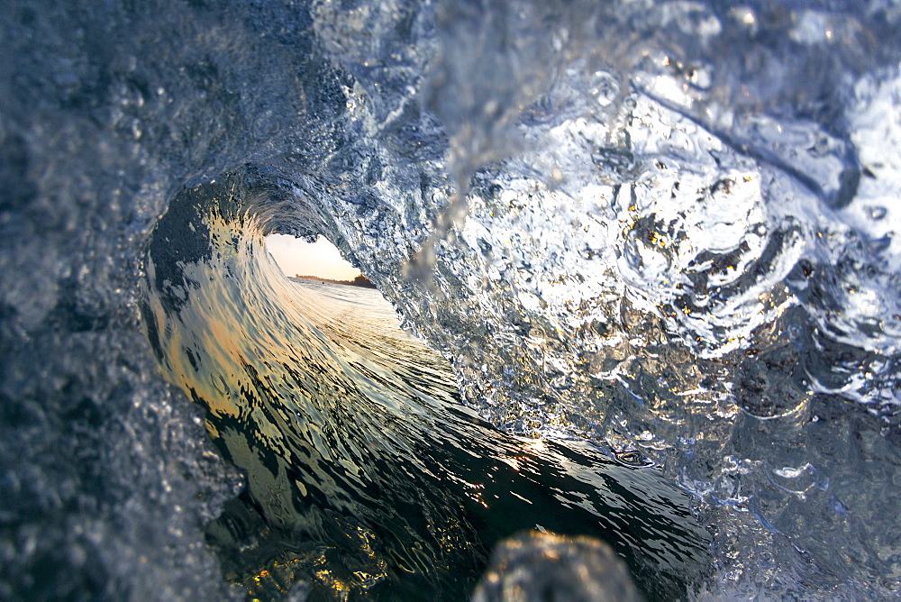 A wave breaking towards the shoreline on the north shore of Oahu, during sunrise.