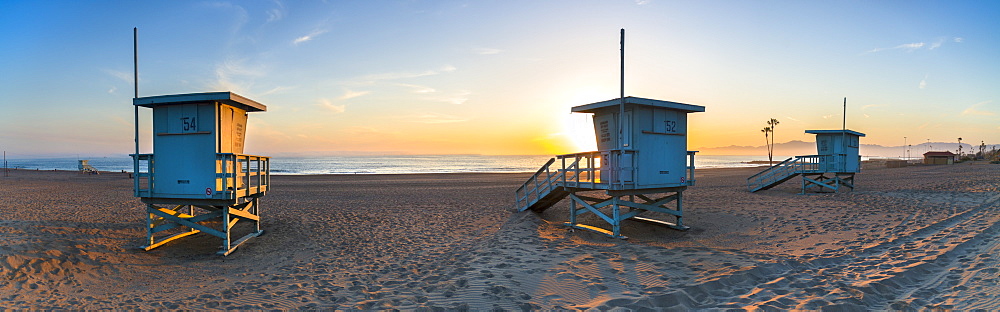 Deserted lifeguard stands at Dockweiler beach, in Los Angeles, during a golden sunset.