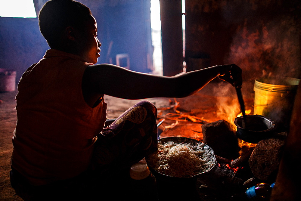 Ester Hodari, age 22 years old, cooks dinner using the traditional three-rock cook stove with a fire in the middle. These cookstoves use a lot of fuel, firewood, and produce a lot of smoke. Ester told us that cooking with this type of stove made her eyes turn red and she often had a chest cough. Her children, ages 5, 2 and 3 months are often with her when she is cooking. Her sister-in-law, Shadya Jumanne, age 11, helps her cook as well. Not long ago Esterâs 3 month-old developed a cough, It kept getting worse and so they took her by motorcycle to the hospital at night. Ester started really worrying about this.  After this Ester and her husband agreed that they needed to buy a clean cookstove and started saving. The girl helping Ester cook in some of the images is her sister-in-law Shadya Jumanne, age 11.  Ester met Solar Sister entrepreneur Fatma Mziray when she married her husband and moved to this village, Mforo near Moshi, Tanzania. Ester said that Fatma is like a mother to her in the village. When Fatma showed Ester the new wood stove she saw that is used less wood and produced less smoke.