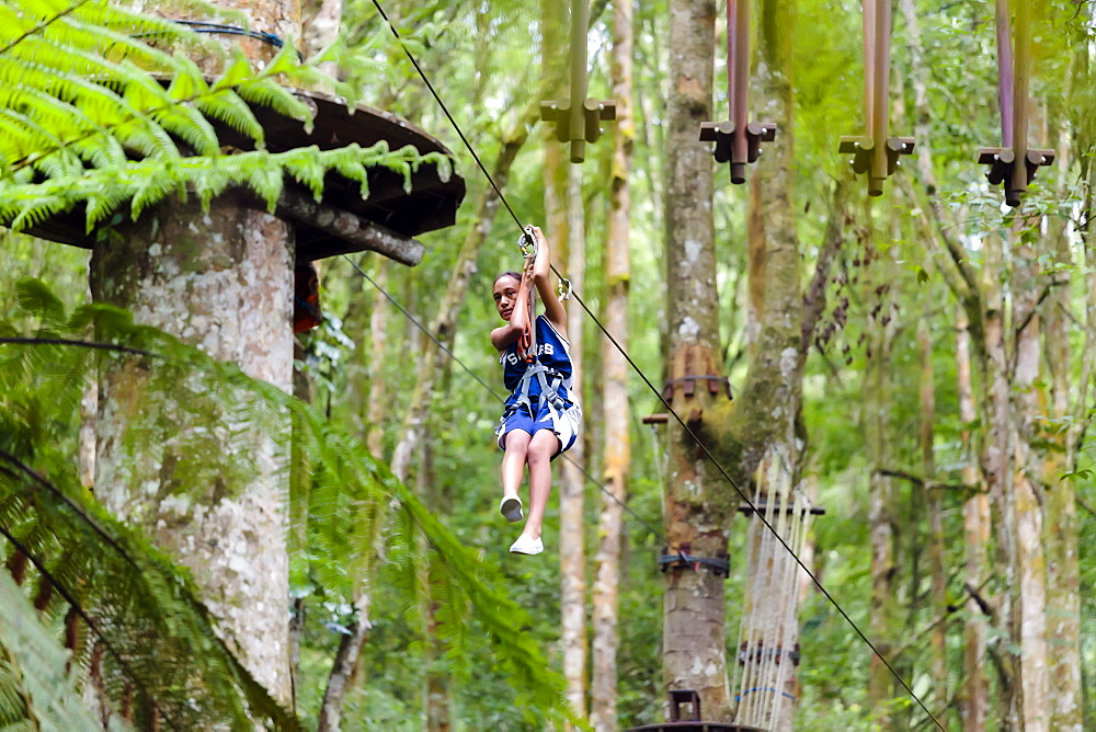 A girl descends a zipline at a Treetop Adventure Park, Bali, Indonesia