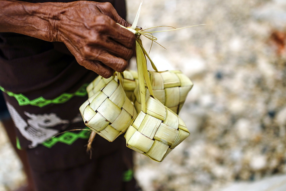 Hand holding traditional baskets of rice, Sumba Island, Indonesia