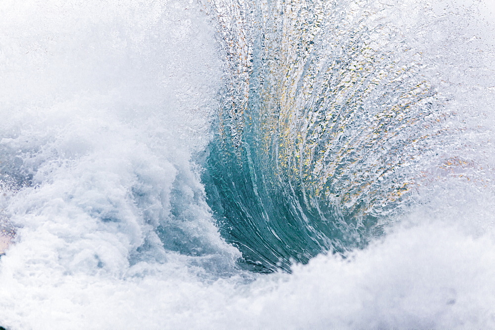 A foamy ocean wave crashing in the early morning dawn light.