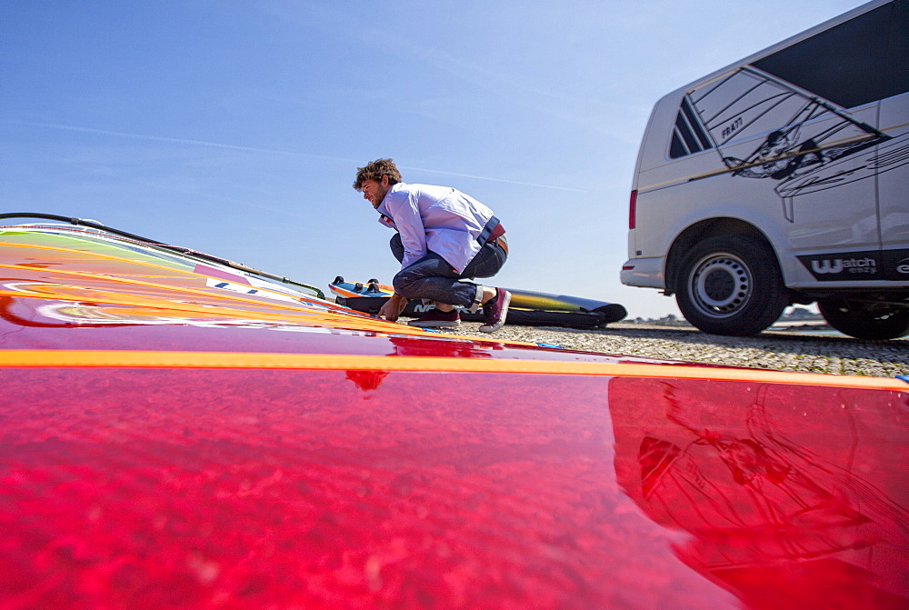 Pierre Le Coq preparing his windsurfing gear on a jetty near his van at Plouguerneau, Brittany, France.