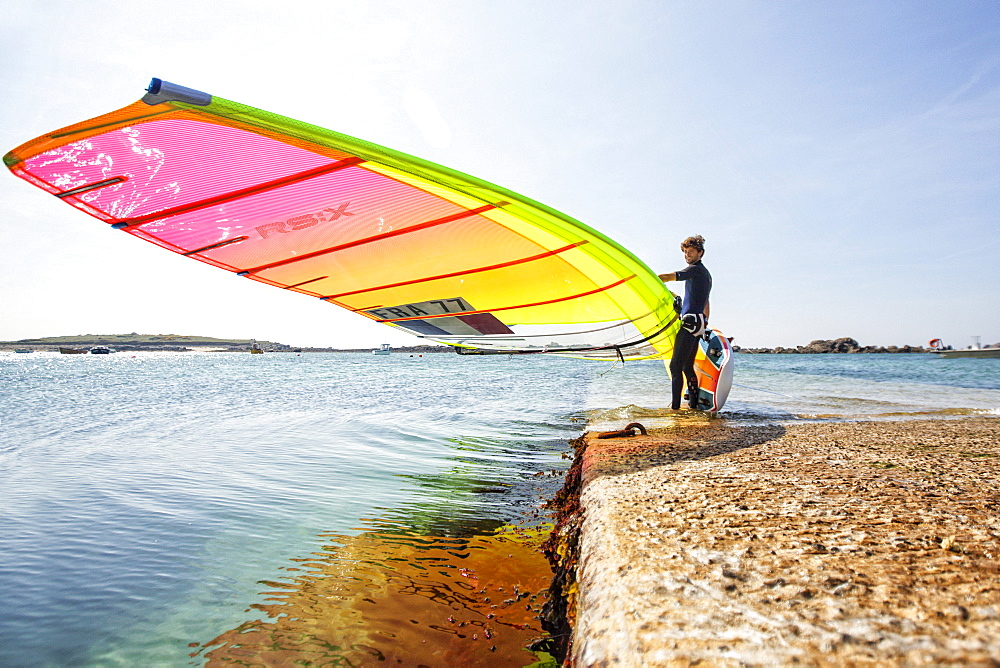 Pierre Le Coq carries his windsurfing board on a jetty at Plouguerneau, Brittany, France.