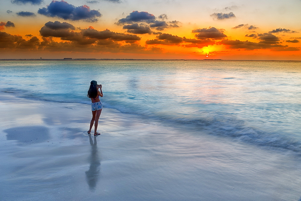 Photograph of woman photographing Caribbean Sea on beach at sunset, Isla Mujeres, Yucatan Peninsula, Mexico