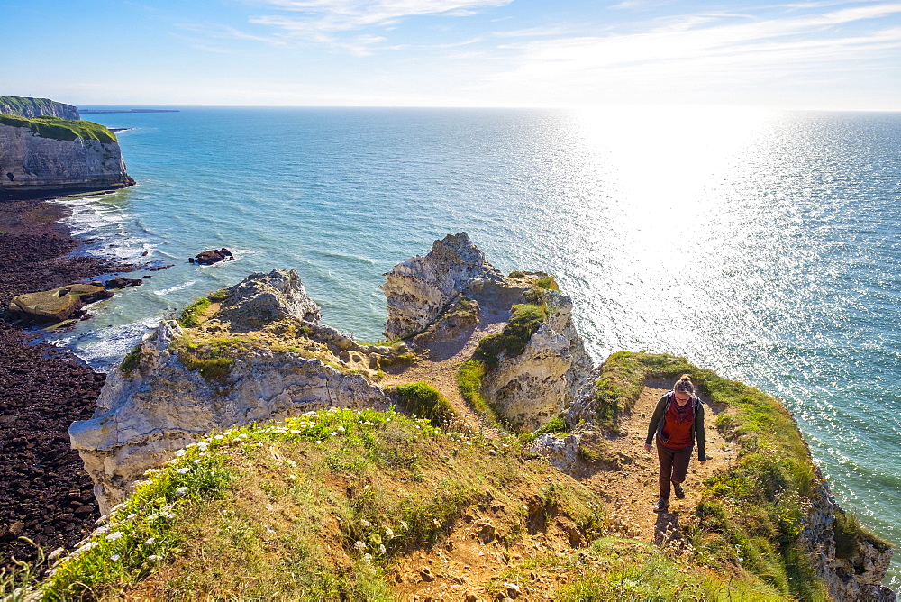 Young woman hiking on cliffs overlooking English Channel, Etretat, Normandy, France