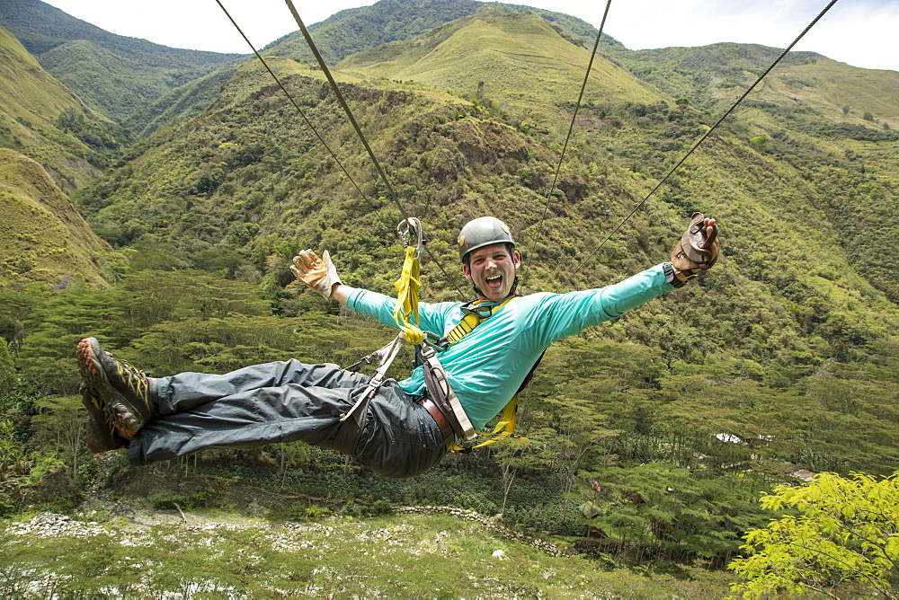 Adventurous man having fun riding on zipline through Amazon forest, Santa Teresa, Cusco region, Peru