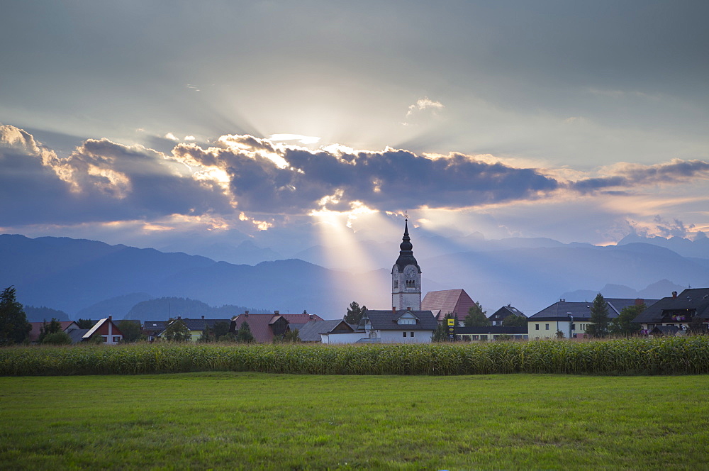 Beautiful scene with sunbeams shining above church in village of Lesce near Bled, Upper Carniola, Slovenia