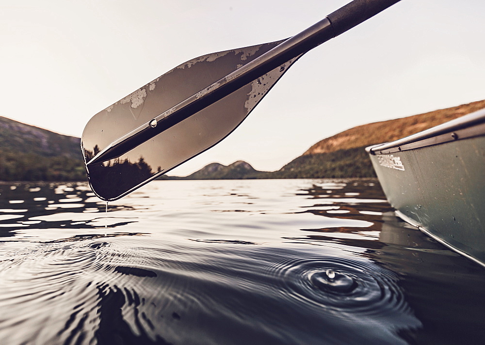 Mountains in Maine's Acadia National Park are framed by a paddle, water droplet and a canoe while they are paddling on Jordan Pond.