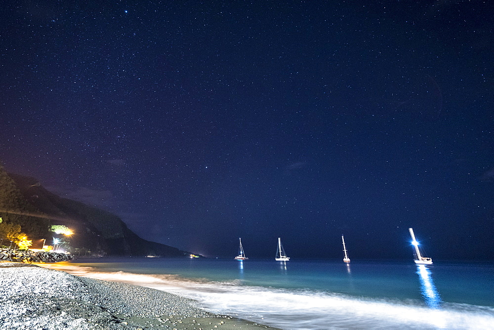 View of sailboats anchored in sea near beach at night, Black Sand Beach, Basse Terre, Guadeloupe