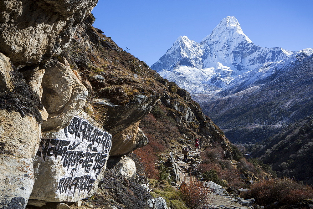 Stone carvings seen in a rock alongside the trail to Everest Base Camp, seen with the peak of Ama Dablam in the background, Khumbu, Nepal