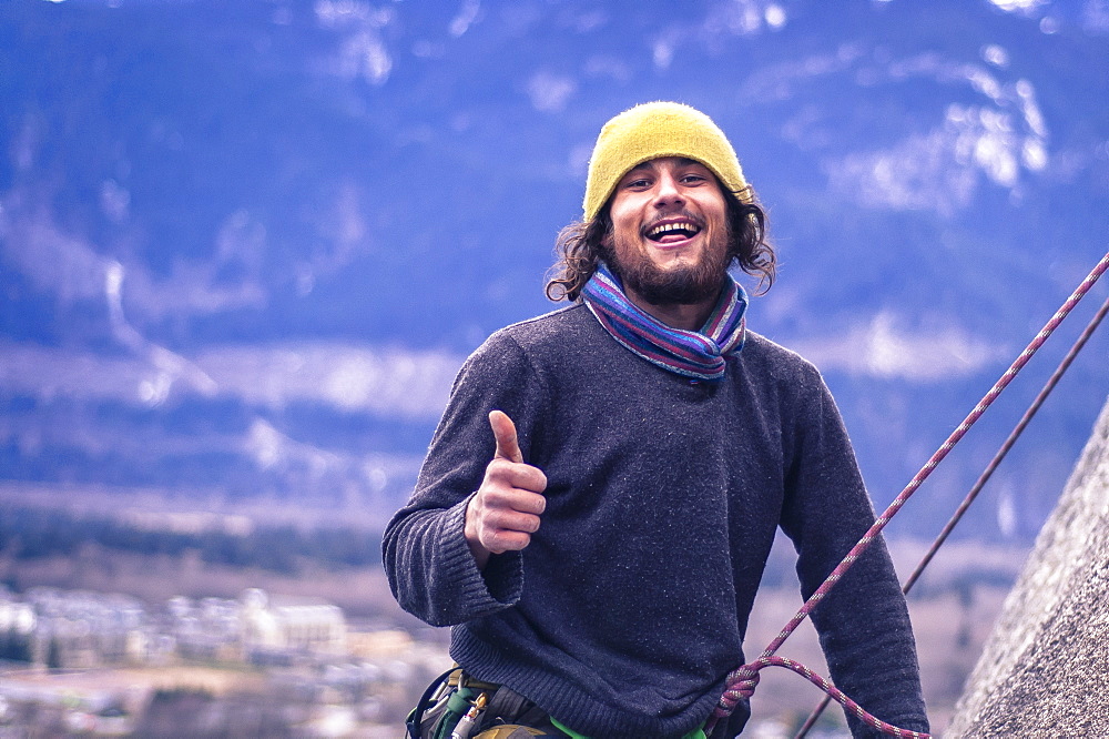 Happy rock climber with thumbs up, knit hat and beard, Squamish, British Columbia, Canada