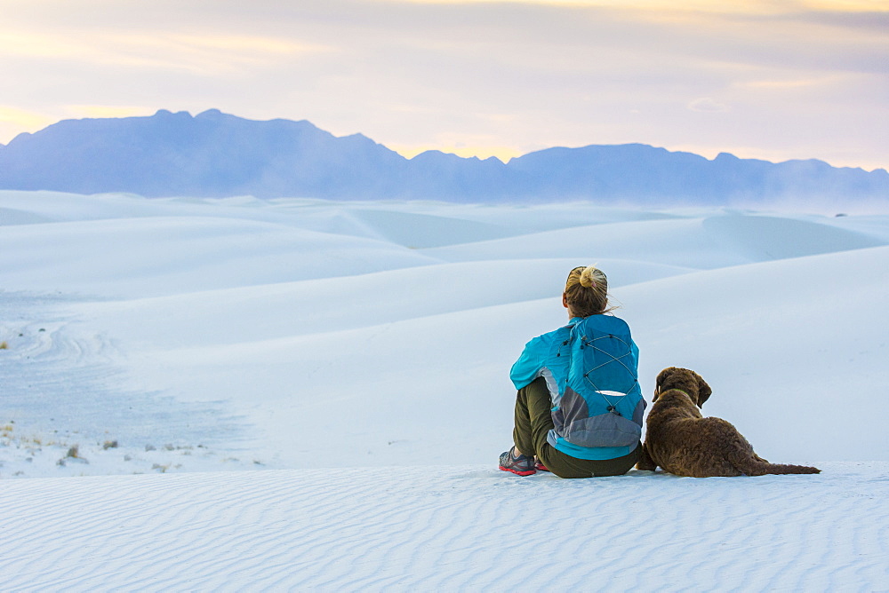 Rear view of woman and dog sitting while hiking in White Sands National Monument, Alamogordo, New Mexico, USA