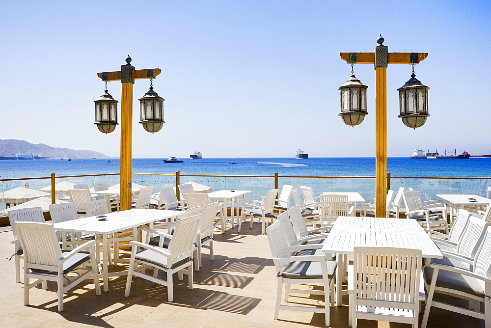 Patio with tables and chairs and Middle Eastern lamps overlooking the Gulf of Aqaba, Aqaba, Jordan