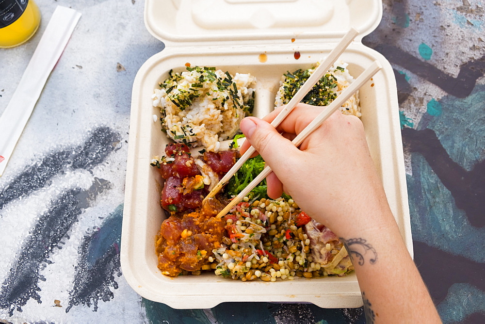 View from above of person eating traditional Hawaiian poke meal with chopsticks, Kona, Hawaii, USA