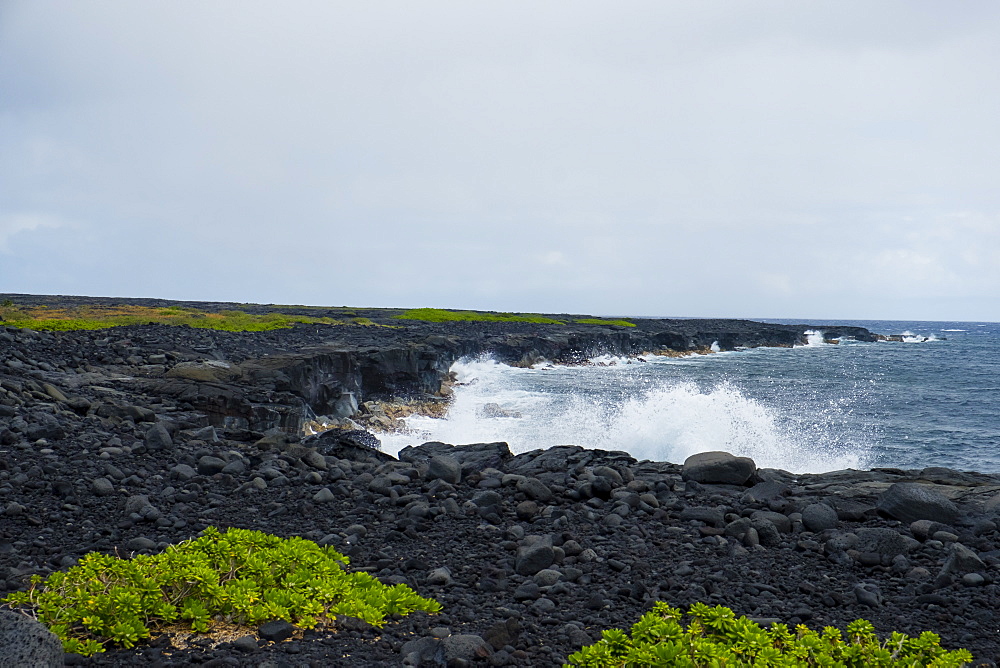 Coastal hiking scenic of the shore with waves crashing against the cliffs along the famed Puna Coast Trail to Halape Beach. The trail is 11.3 miles of rugged hiking for backpackers with no shade or water in the extreme terrain of Hawaii Volcanoes National Park, Hawaii, USA