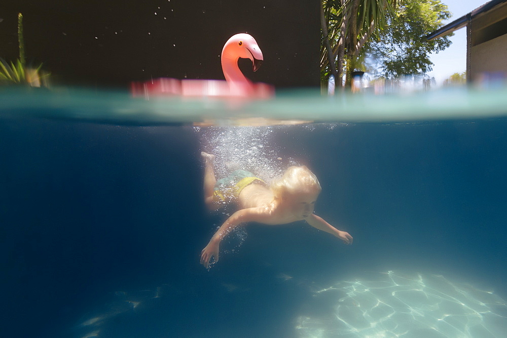 Underwater view of single blonde boy swimming in pool