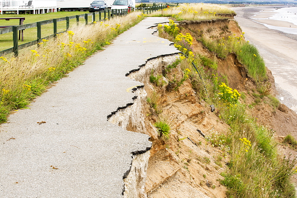 A collapsed coastal road at Barmston on Yorkshires East Coast, near Skipsea, UK. The coast is composed of soft boulder clays, very vulnerable to coastal erosion. This section of coast has been eroding since Roman times, with many villages having disappeared into the sea, and is the fastest eroding coast in Europe. Climate change is speeding up the erosion, with sea level rise, increased stormy weather and increased heavy rainfall events, all playing their part.