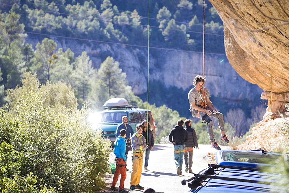 Male climber getting lowered from popular climbing crag, Margalef, Catalonia, Spain