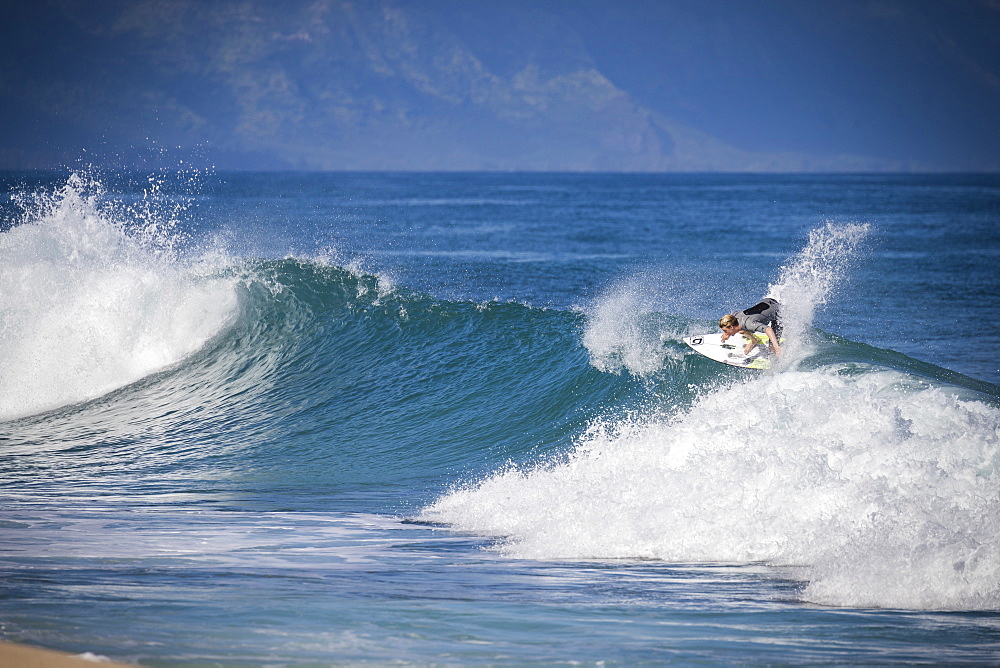 Distant view of man in wetsuit surfing in sea