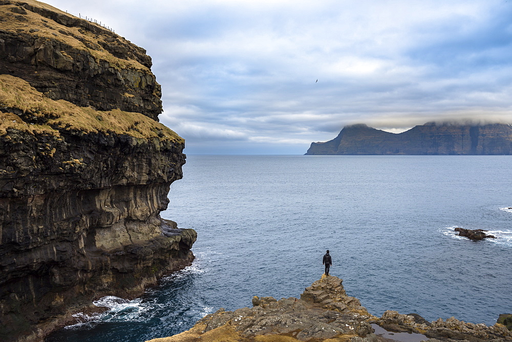 Rear view of man standing on seashore, Faroe Islands, Denmark