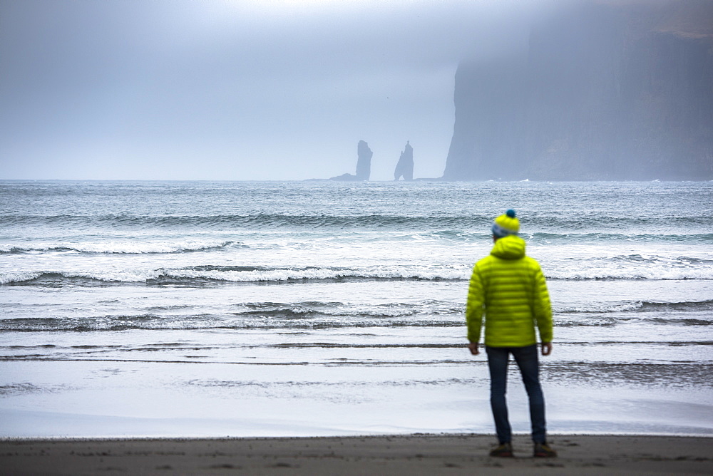 Rear view of man standing on seashore, Faroe Islands, Denmark