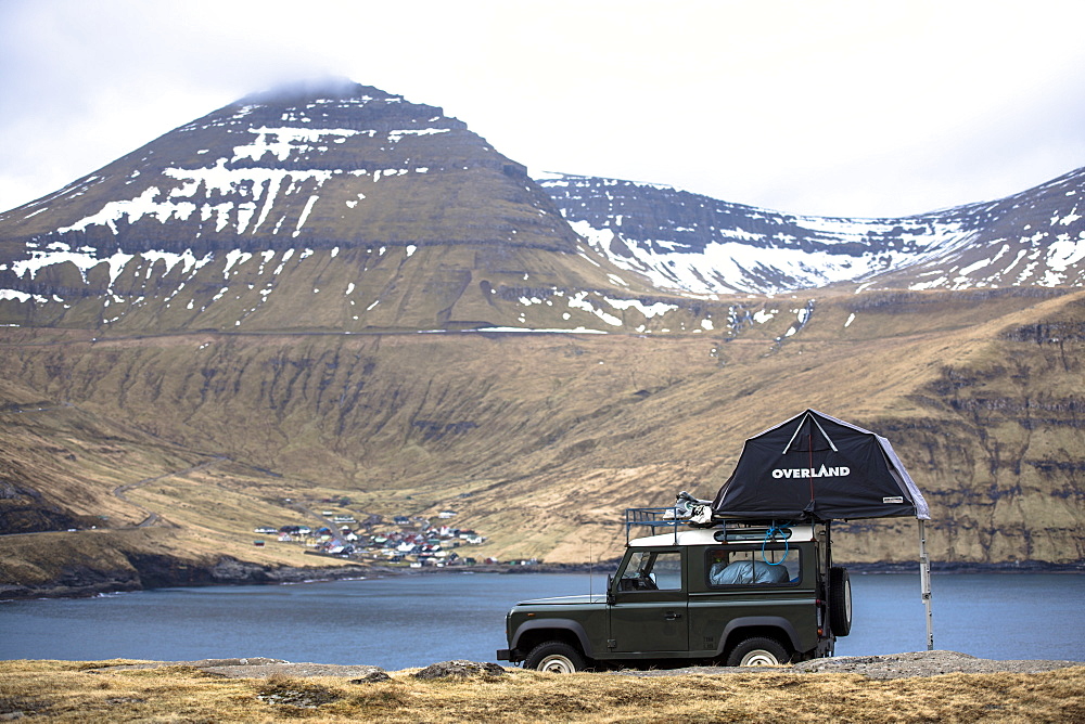 Side view of single 4x4 car with tent parked against mountains, Faroe Islands, Denmark