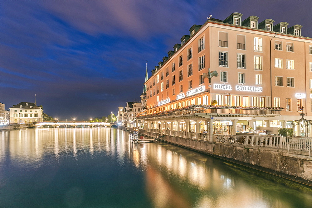 IlluminatedÂ hotel building by river LimmatÂ at night, Zurich, Switzerland