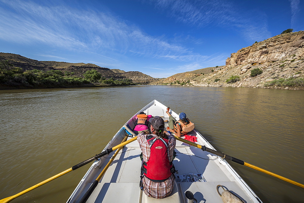 Man and two women sailing across calm Green River in Desolation Canyon, Utah, USA