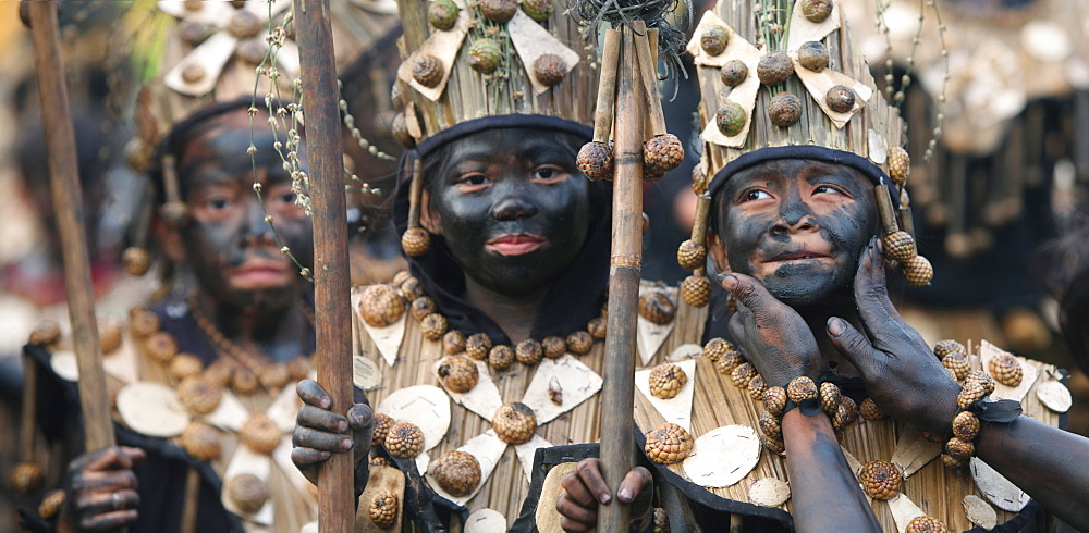 Three children in tribal costumes with black smeared faces at Ati Atihan festival, Kalibo, Aklan, Panay Island, Philippines