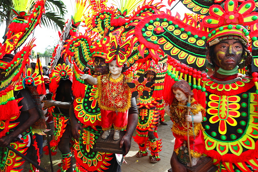 People with black smeared faces in tribal costumes holding Jesus Child figurines at Ati Atihan festival, Kalibo, Aklan, Panay Island, Philippines