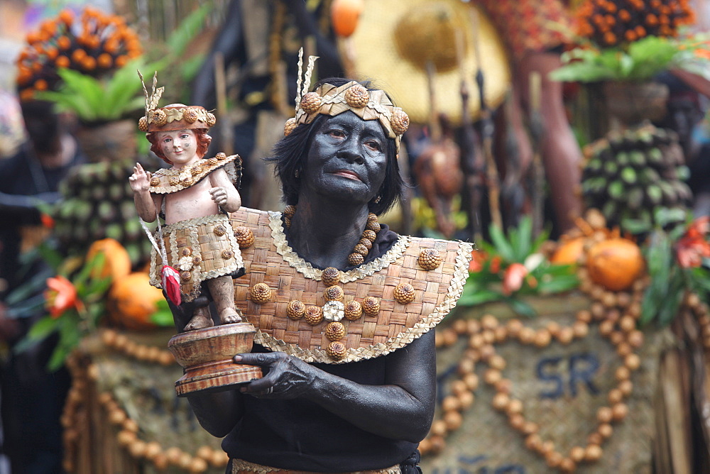 Elderly woman holding Santo Nino figurine at Ati Atihan festival on blurred background, Kalibo, Aklan, Panay Island, Philippines