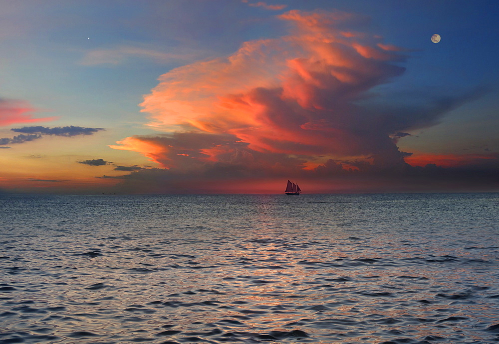 Distant view of sloop in sea under moody sky at sunset, Boracay, Aklan, Philippines